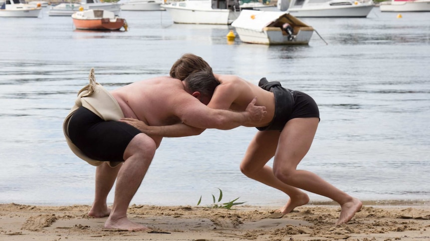 Jack Carlson and John Trail wrestle on the beach