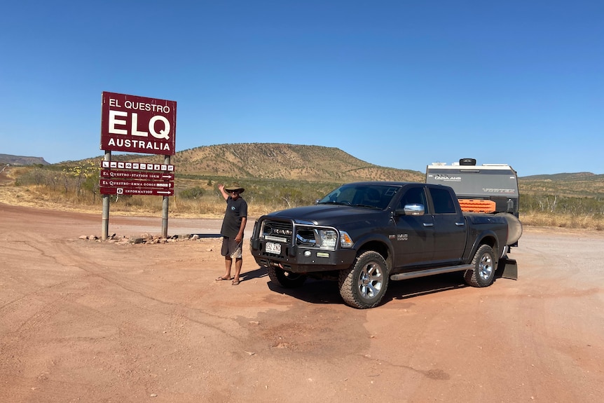 A man stands next to a big ute and caravan in a remote landscape