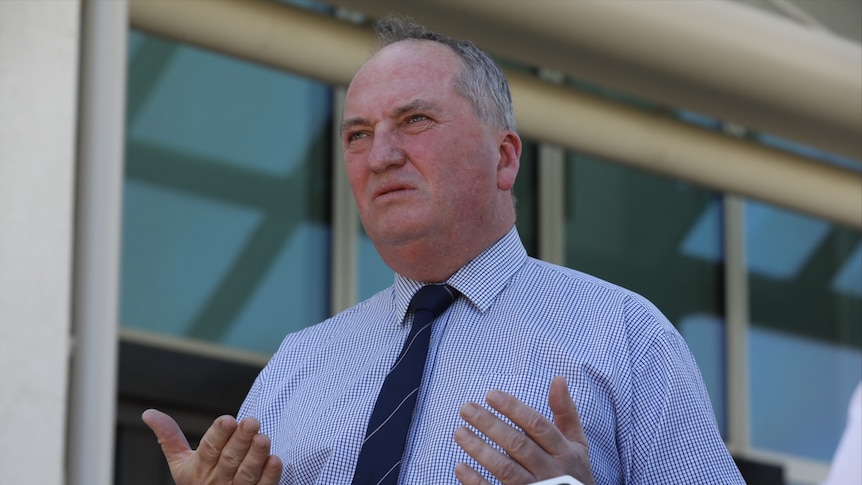 Barnaby Joyce in a shirt and a dark tie looks to the left of camera with his lips pursed and his palms facing upwards