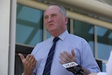 Barnaby Joyce in a shirt and a dark tie looks to the left of camera with his lips pursed and his palms facing upwards