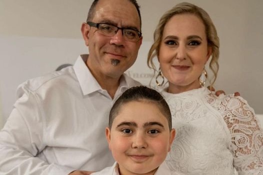A family of three all dressed in white looking at the camera. 