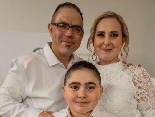 A family of three all dressed in white looking at the camera. 