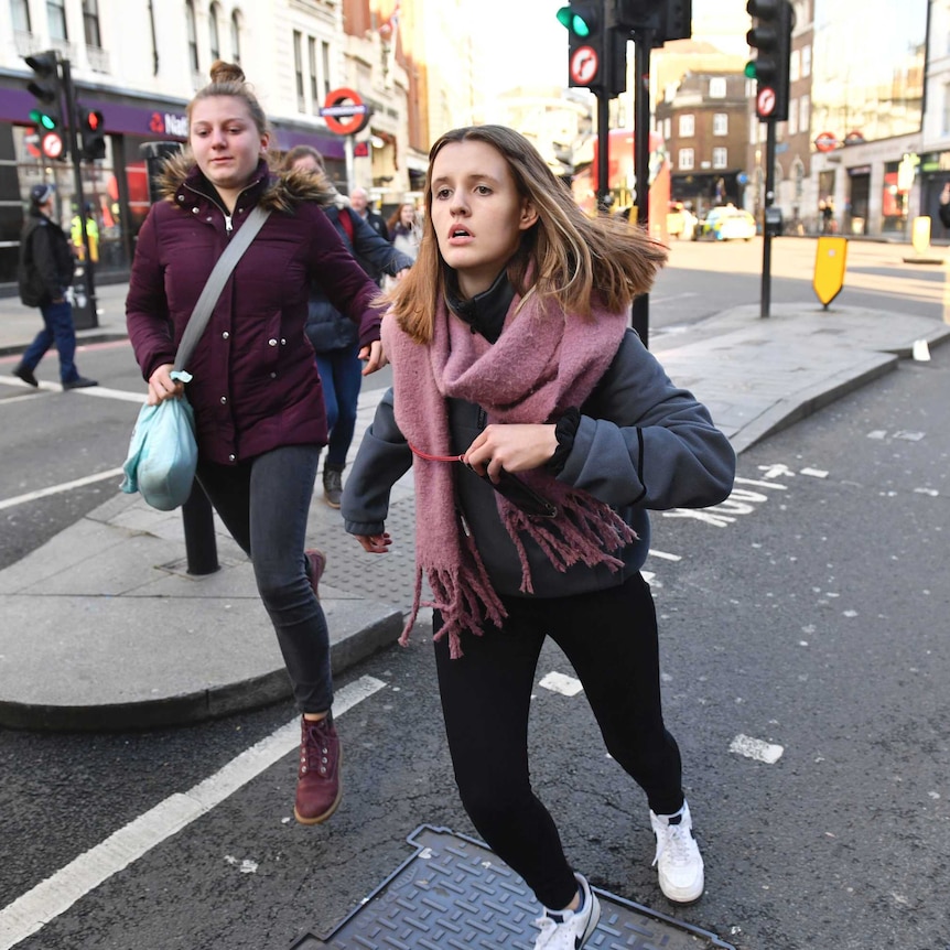 Two women run along a London street.