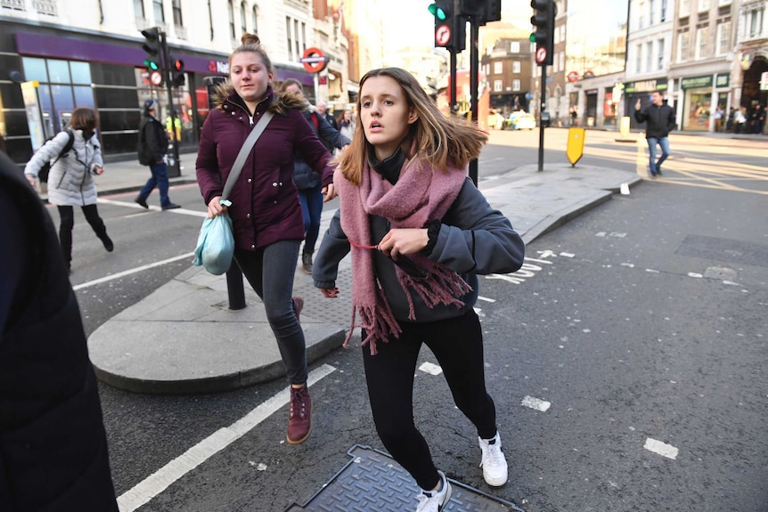 Two women run along a London street.