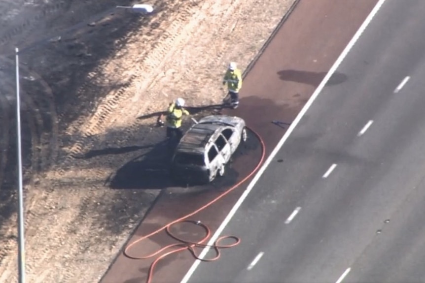 An aerial shot of firefighters with the burnt car.