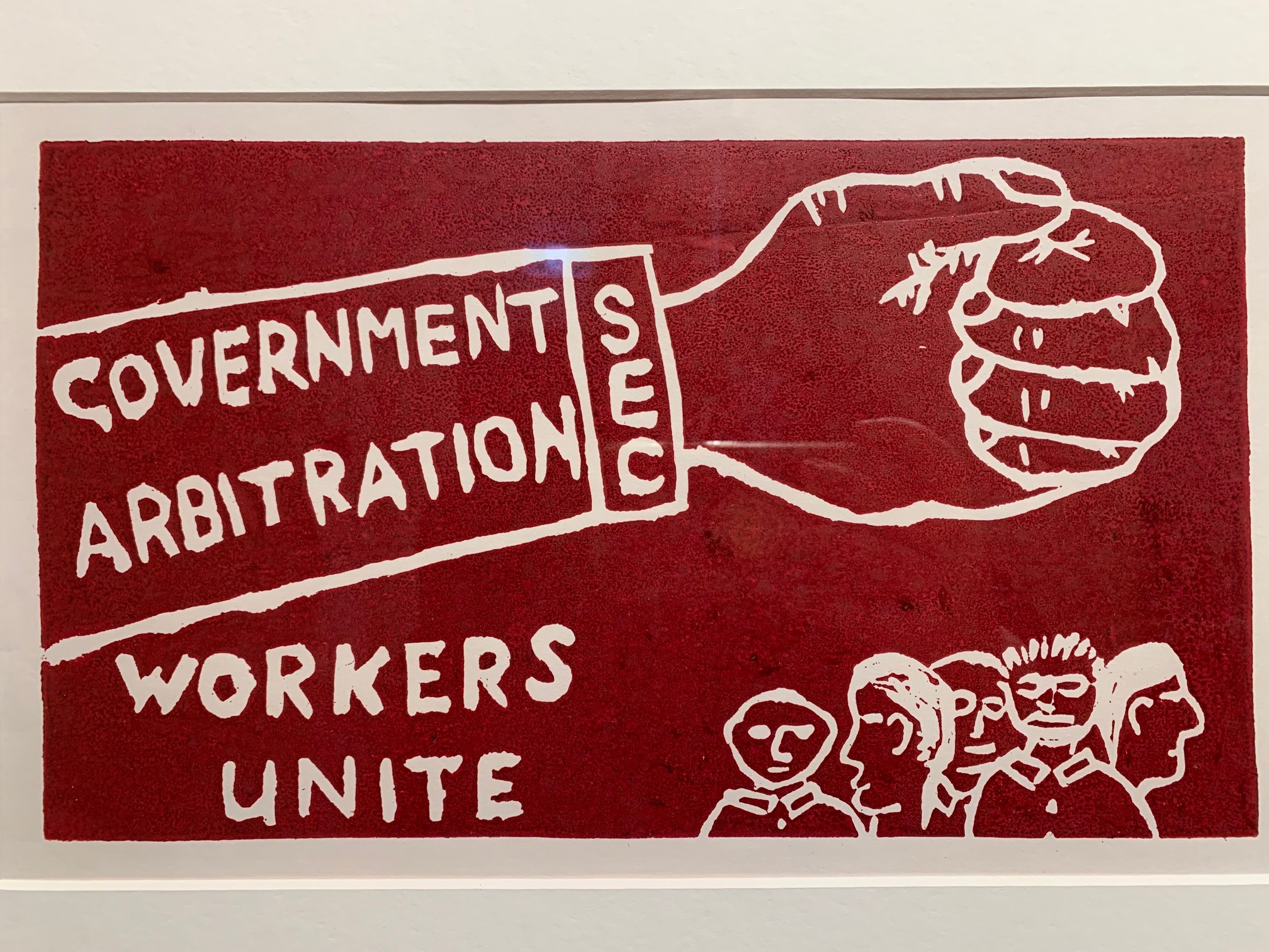 A red poster with white writing that says government arbitration, workers unite.