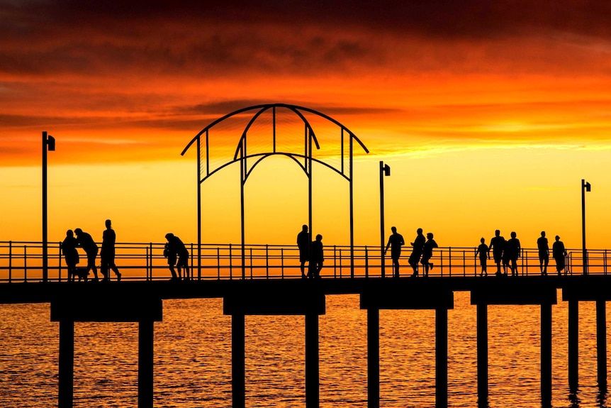 People on a pier during sunset.