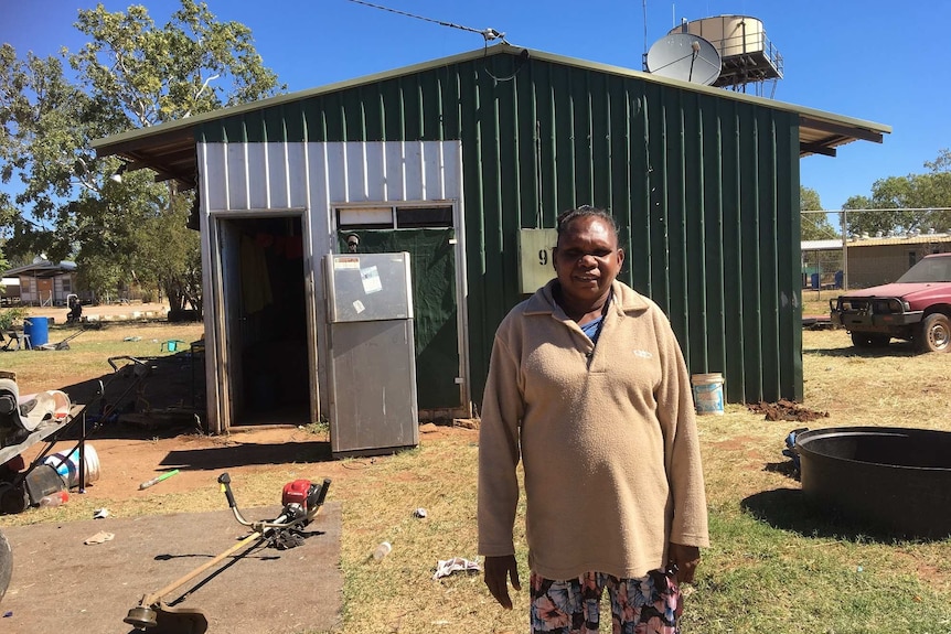 Samantha Campbell stands in front of a tin shed house.