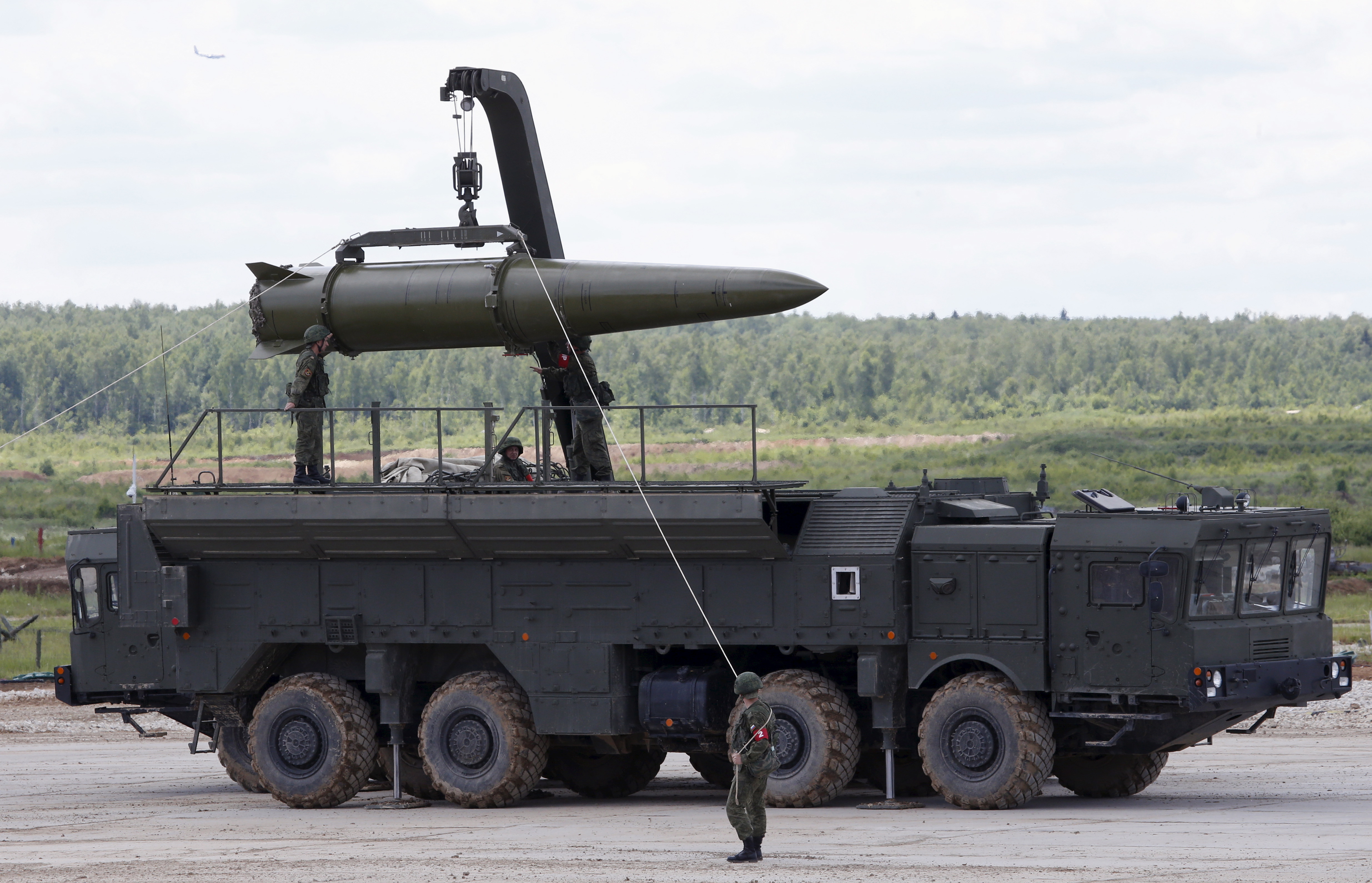 Equip an Iskander tactical missile system. They stand in camo on the back of a road tank, with a missile being loaded on top.