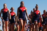 Women in AFLW uniforms stride together