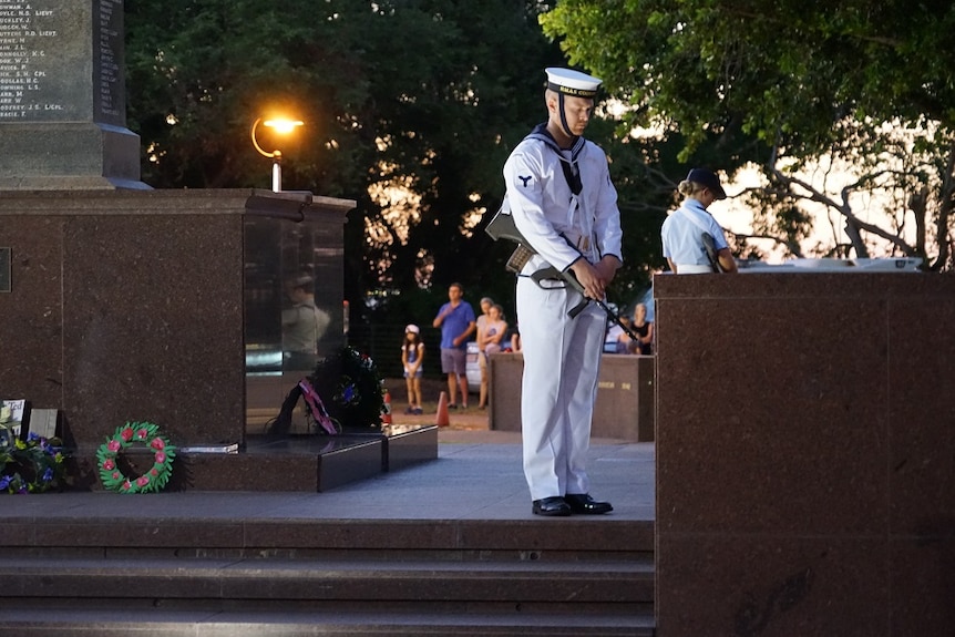 A soldier with his head bowed near the cenotaph