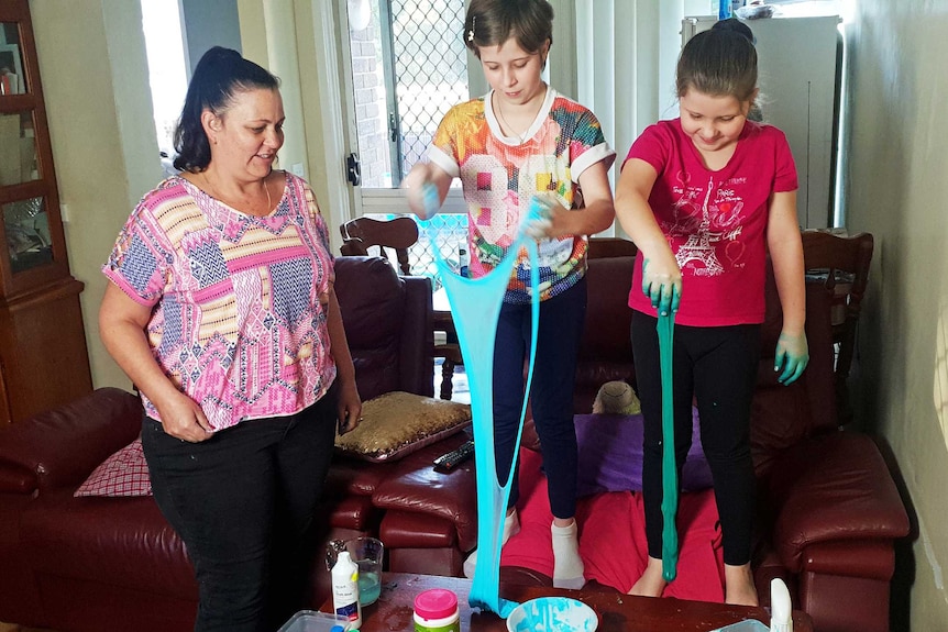 Michelle Sheean looks on as her children play with slime.