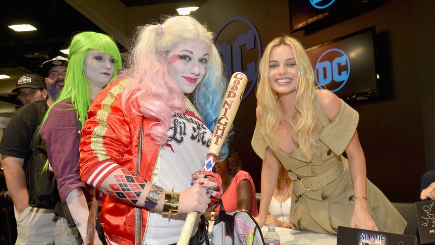 Margot Robbie leans over to pose with fan in costume