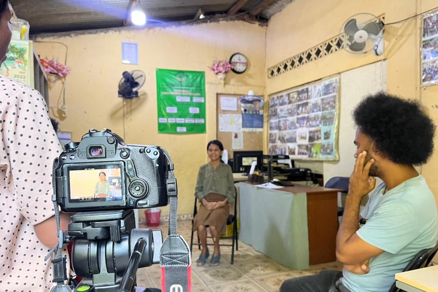 A EOS 70D camera filming a person seated in an office room location while two others stand aside form the camera interviewing.