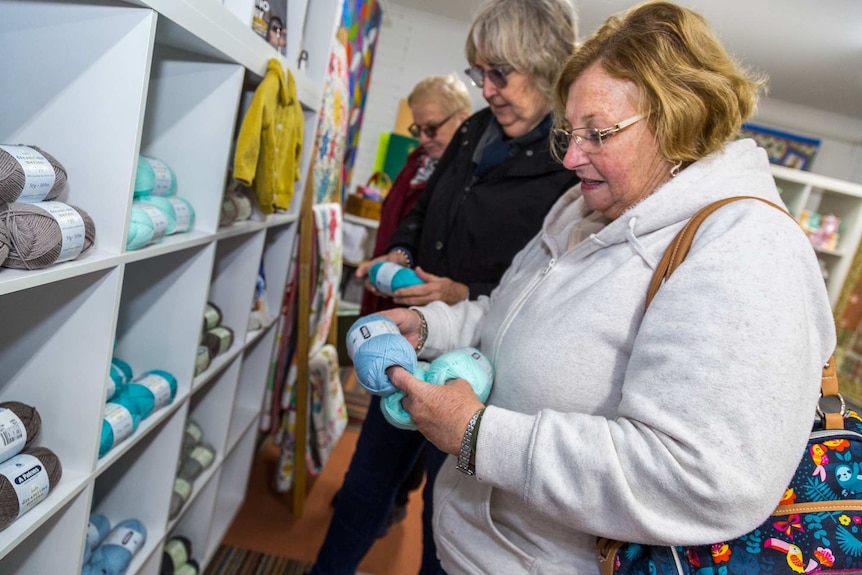 Three women look at yarn in a haberdashery store.