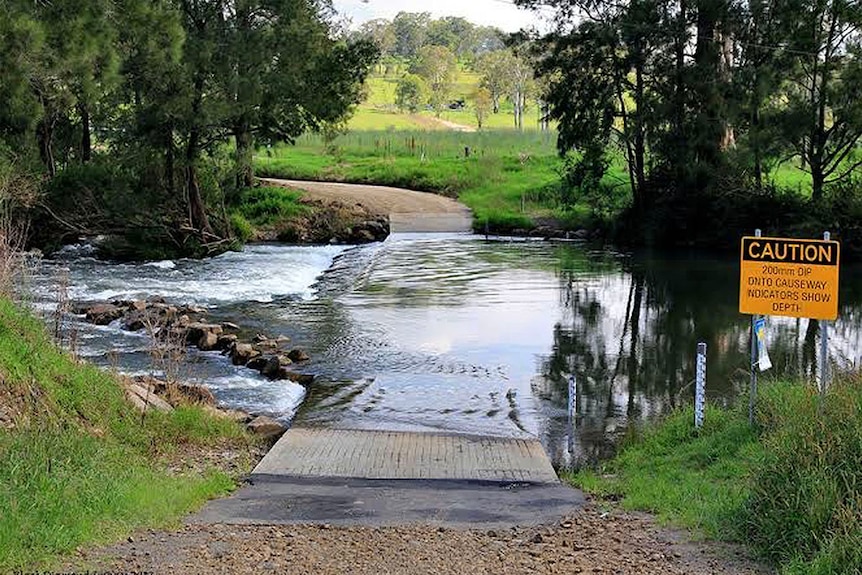 Barrington River with water flowing over the crossing as road disappears into water