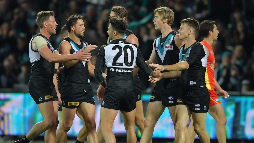 A collection of Port Adelaide players exchange congratulations after a goal.
