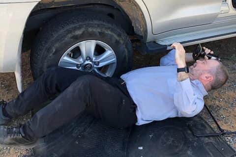 a man lays on the ground changing a tyre