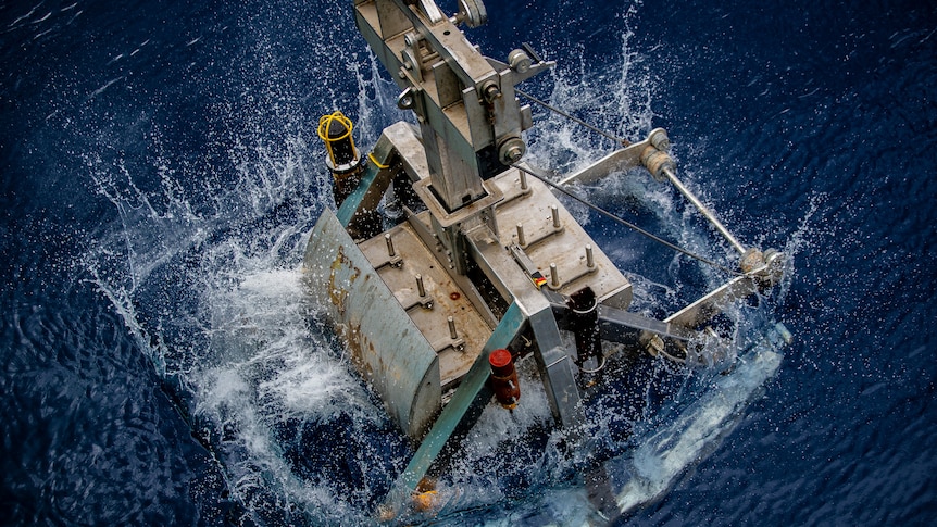 A large machine being plunged into the ocean.