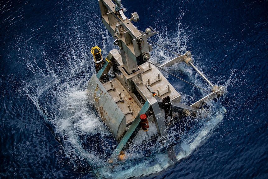 A large machine being plunged into the ocean.