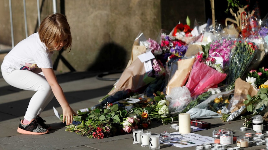 A girl leaves flowers for the victims of an attack on concert-goers at Manchester Arena, in central Manchester.