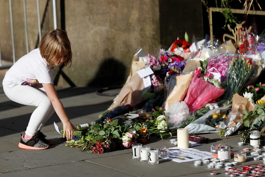 A girl leaves flowers for the victims of an attack on concert-goers at Manchester Arena, in central Manchester.