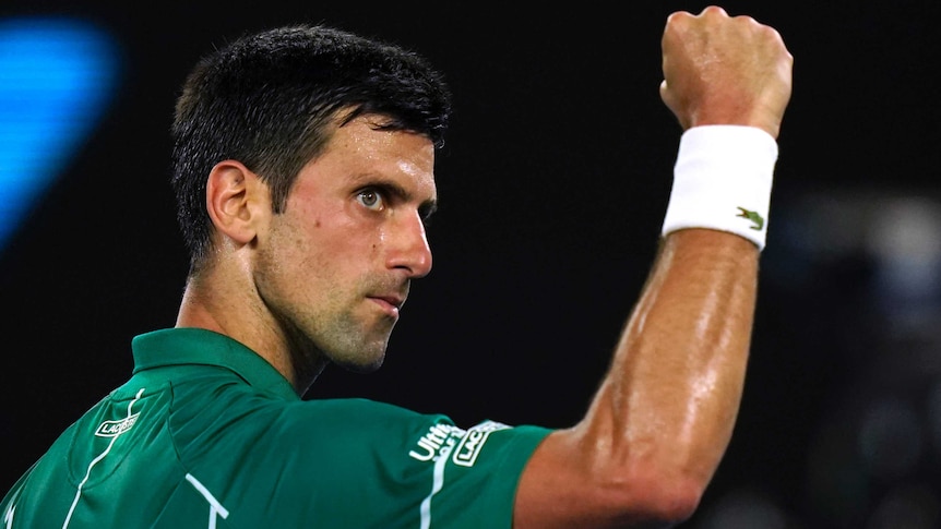 A tennis player pumps his fist as he looks at he crowd after a winning point.