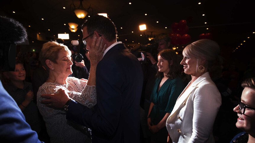 Daniel Andrews' mother, Jan, places her hands on his face as he arrives at Labor's election party.