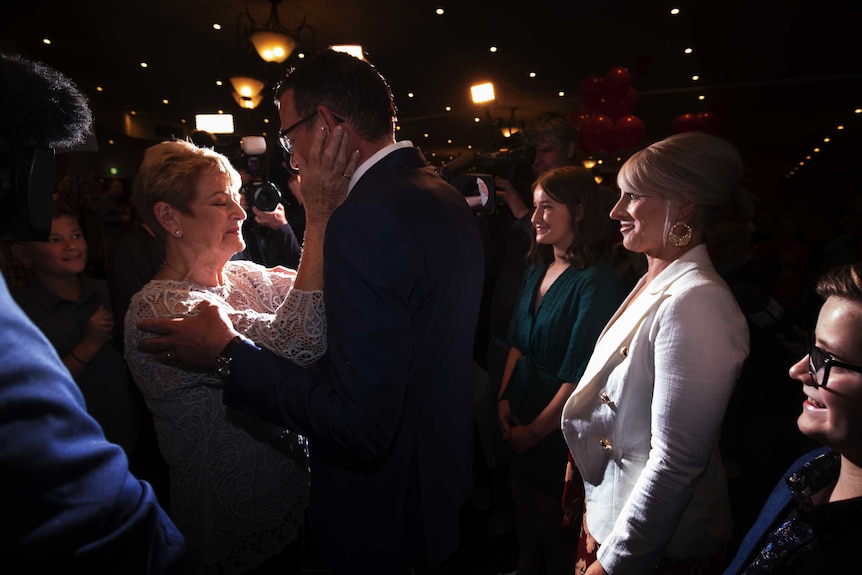 Daniel Andrews' mother, Jan, places her hands on his face as he arrives at Labor's election party.