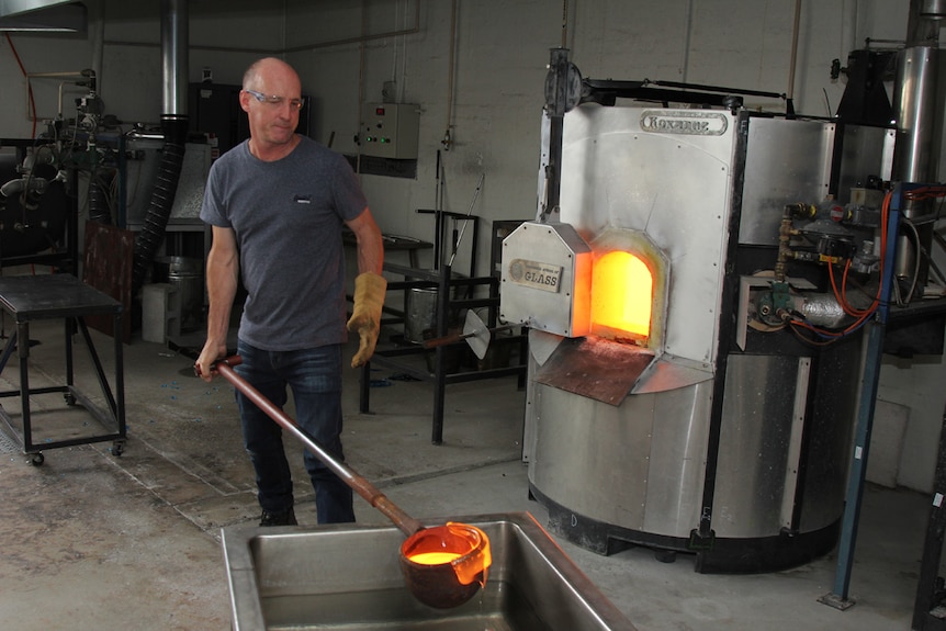 Man standing new to furnace with molten glass