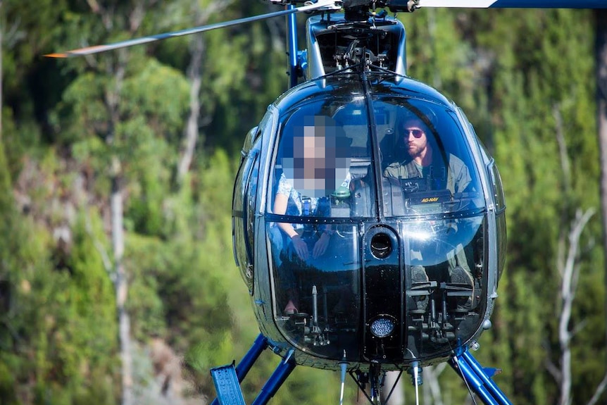 Helicopter pilot John Osborne at the controls of an Osborne Aviation chopper with unidentified passenger