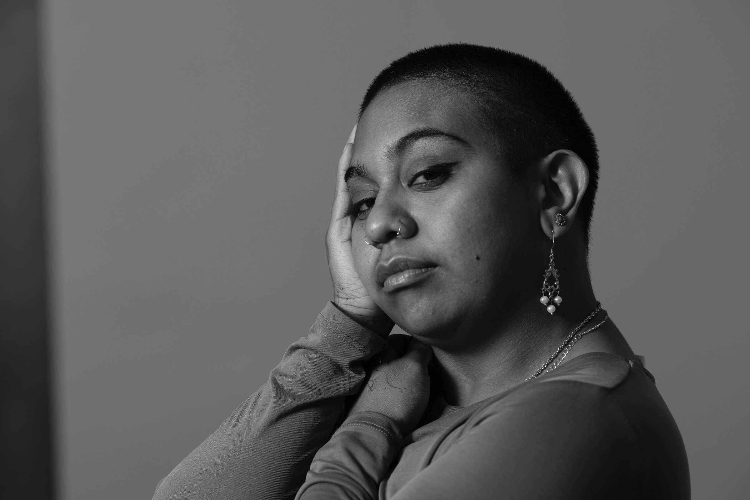 Emily Wurramara with her head in her hand in black and white. 