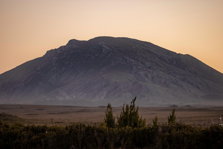 Una montaña rocosa de color azul y un cielo crepuscular amarillento