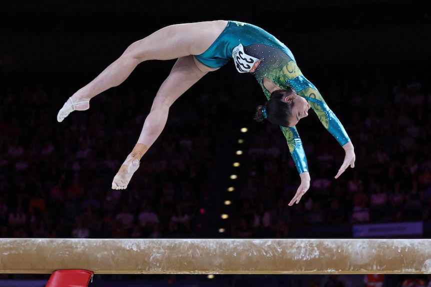 An Australian gymnast arches her back as she does a back flip on the balance beam at the Commonwealth Games.
