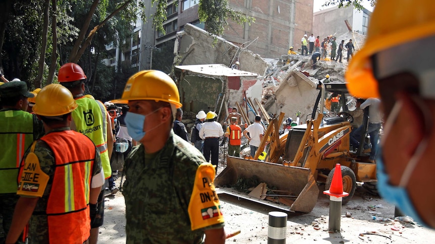 Soldiers and residents in hard hats work at the site of a destroyed building in Mexico City.
