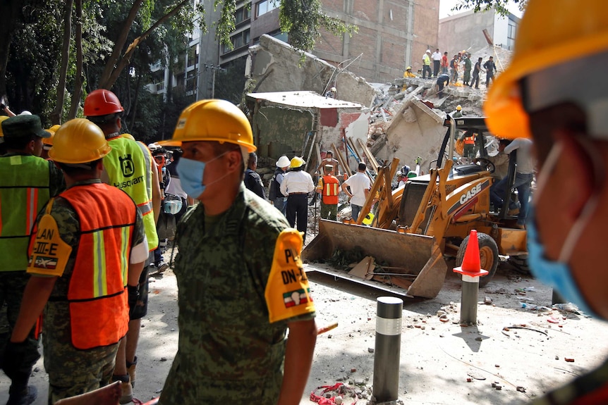 Soldiers and residents in hard hats work at the site of a destroyed building in Mexico City.