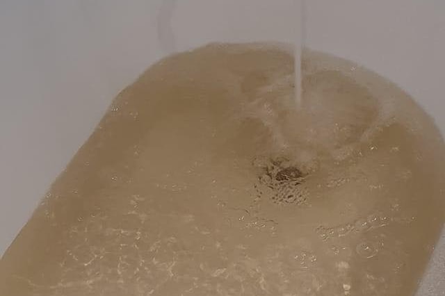 Water coming out of a bath tub tap a light brown colour