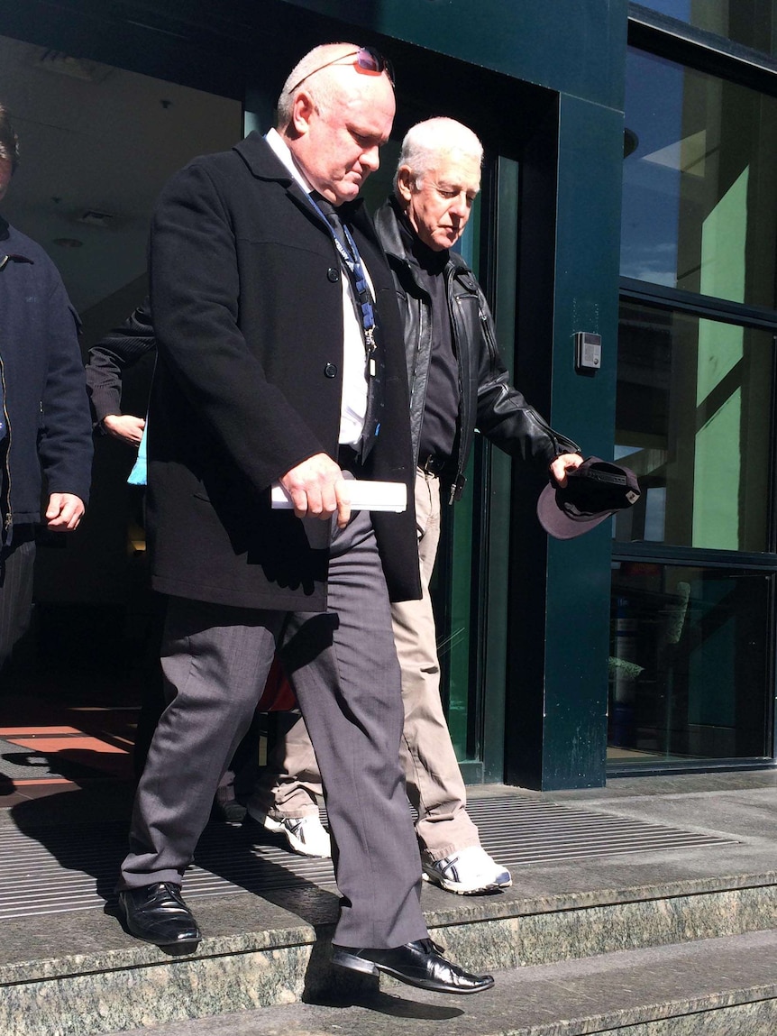 Convicted criminal John Killick, right, is led from Police HQ in Brisbane after surrendering.