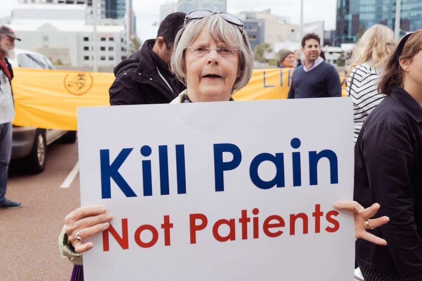 A woman holds up a white sign reading 'Kill Pain Not Patients'.