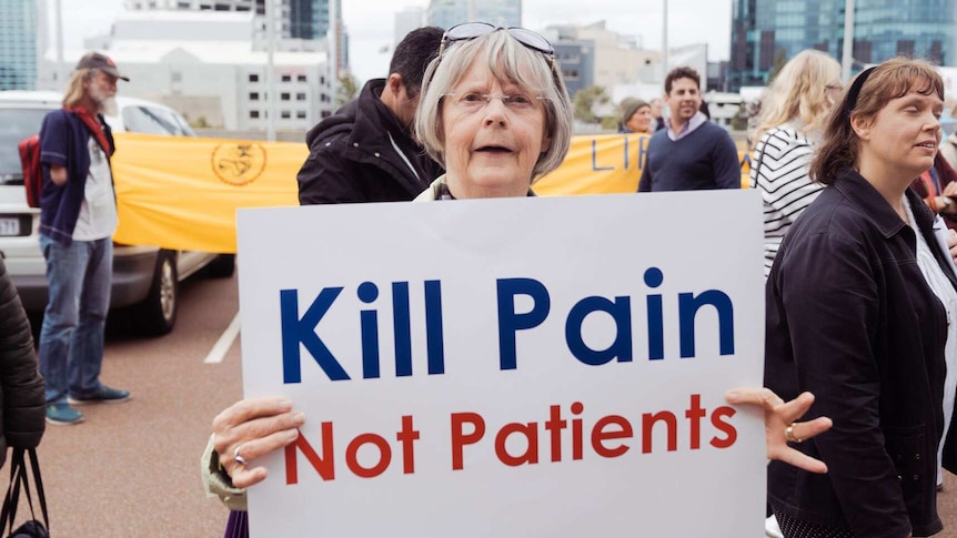 A woman holds up a white sign reading 'Kill Pain Not Patients'.