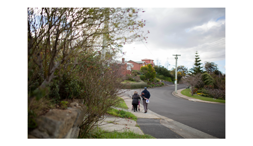 Two people walk on a footpath up a hill.