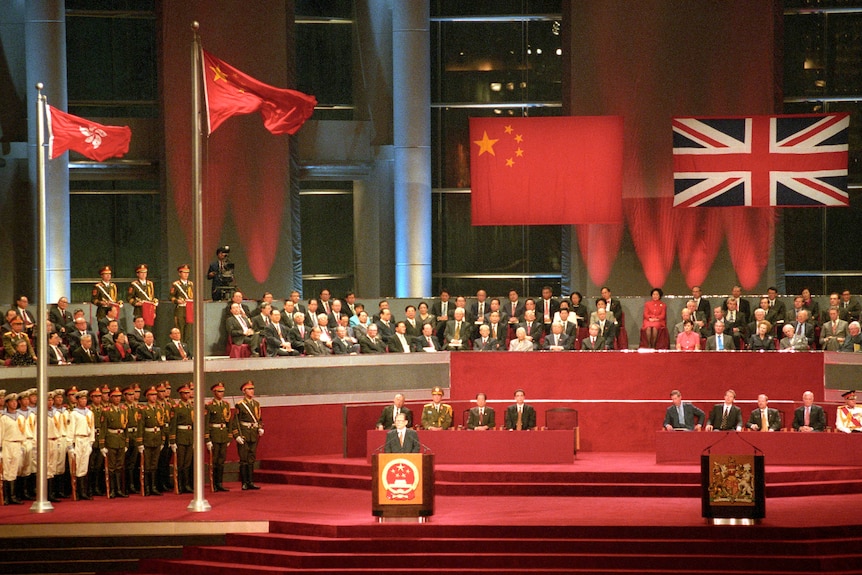 A wide shot of Jiang Zemin standing behind a podium at a ceremony.