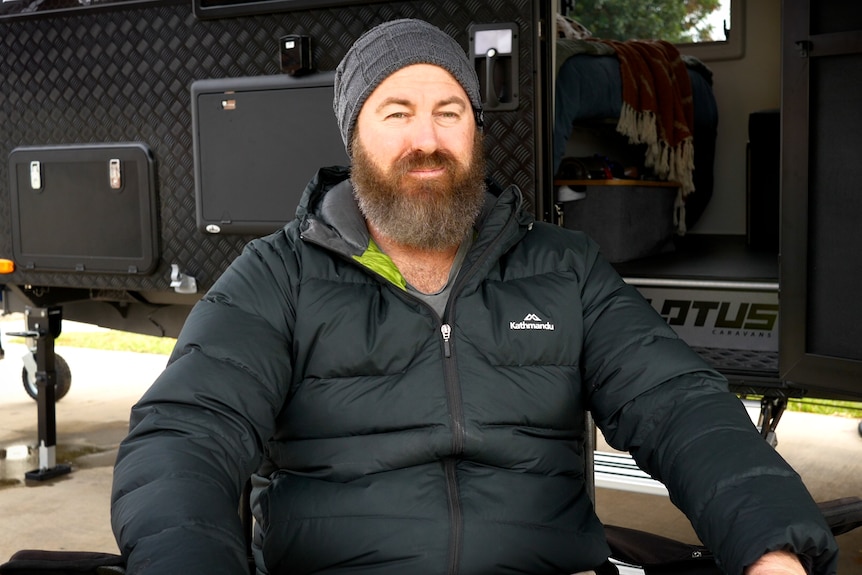 Homme avec une barbe devant une caravane