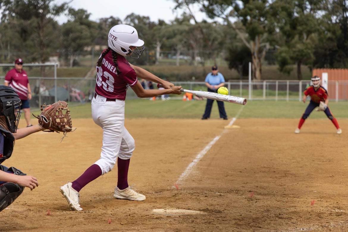 A girl in maroon playing softball. 