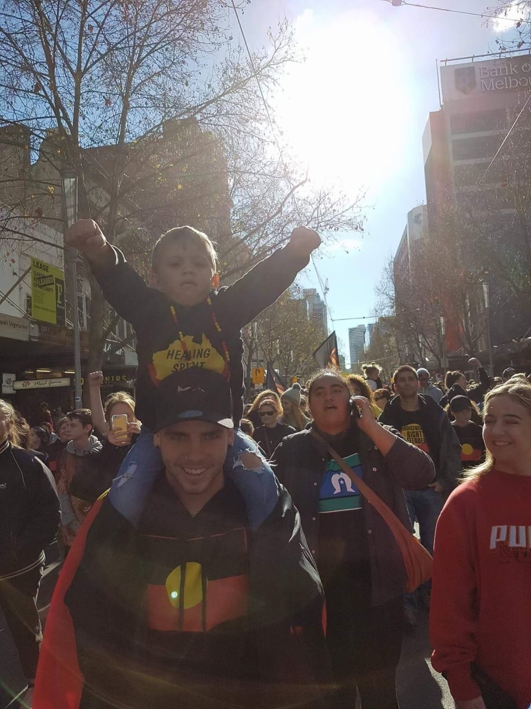 Child sitting on his dad's shoulder at a march protest