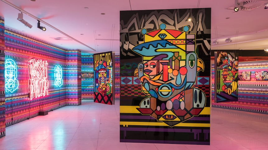 a vibrant graffiti style artwork hangs in a pink gallery space.