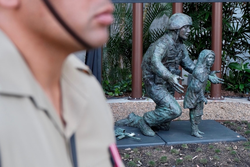 A bronze statue, by artist Wayne Strickland, depicts an Australian soldier helping an Afghan child.