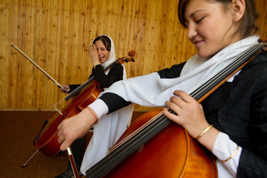 Fekiria, 14, practices the cello during class alongside Zahra, 14, at the Afghanistan National Institute of Music.