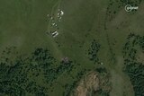 Satellite image of a plane wreckage in a rural-looking area with trees, fields and a few buildings nearby
