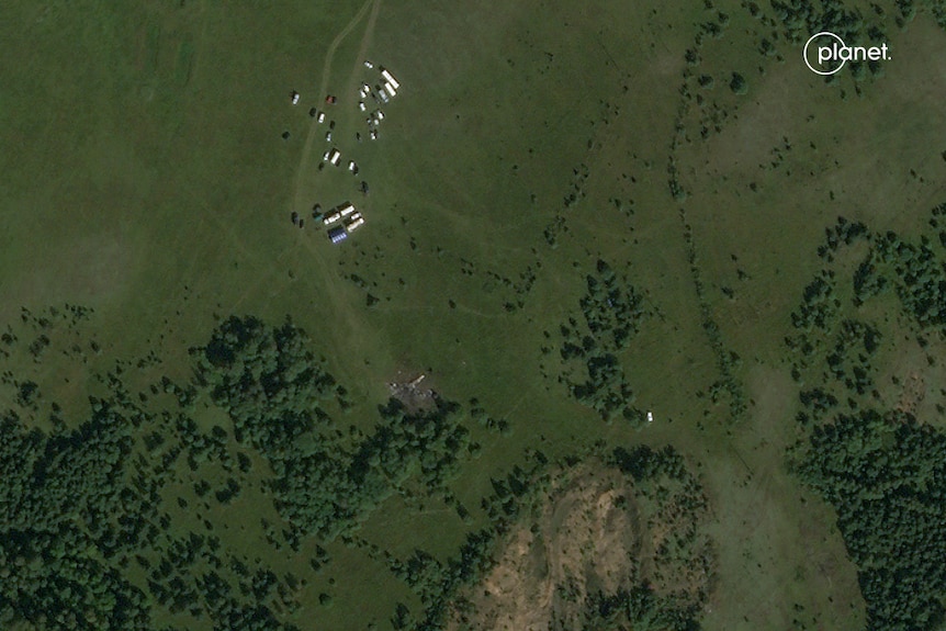 Satellite image of a plane wreckage in a rural-looking area with trees, fields and a few buildings nearby